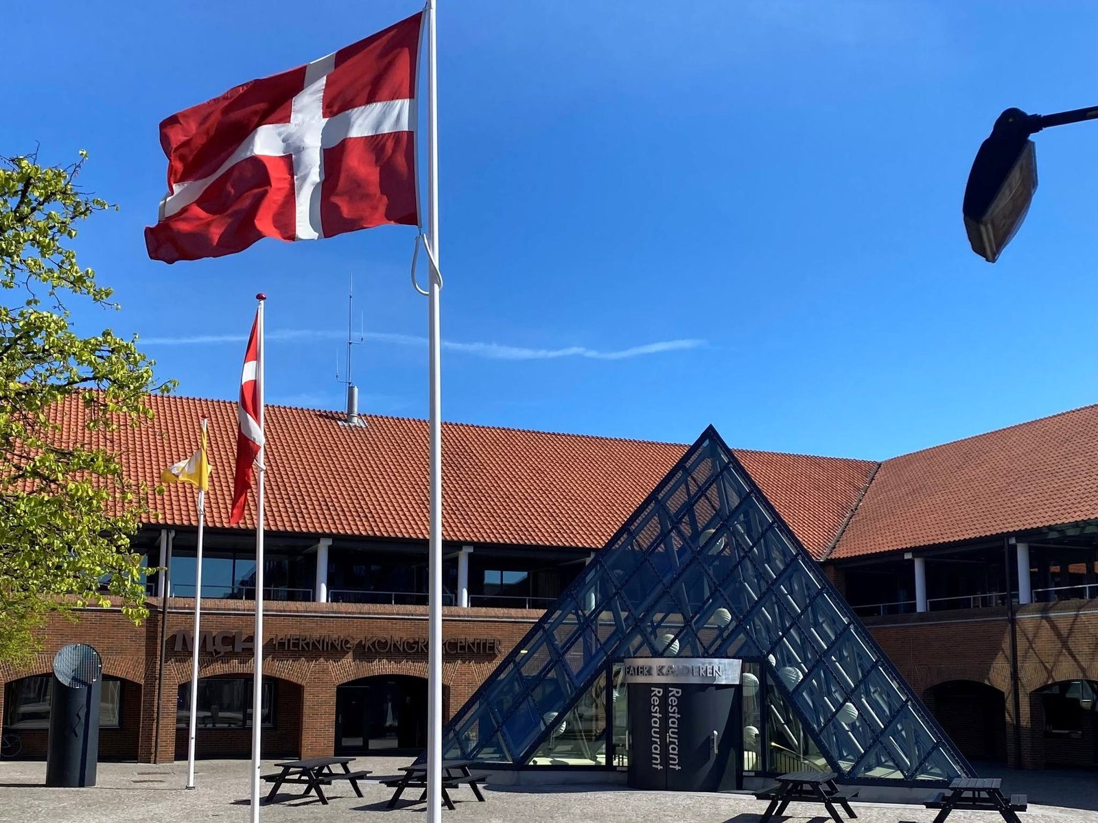 Danish flags outside the MCH Herning Kongrescenter, with its glass pyramid entrance